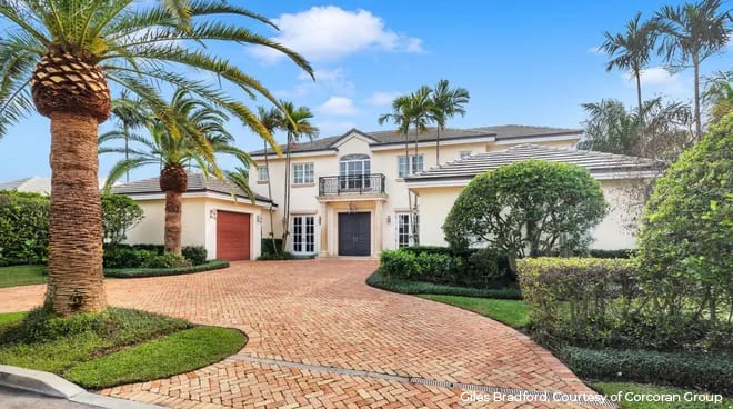 Front of Palm Beach Island home with palm trees and driveway