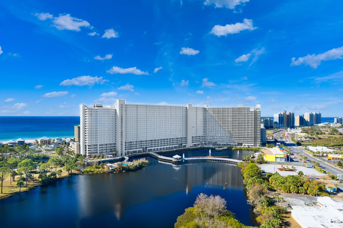 A large, white high-rise resort complex with multiple balconies and windows. 