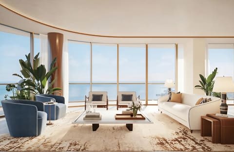 Luxury condo living room with floor-to-ceiling windows overlooking the water and cream sofas.
