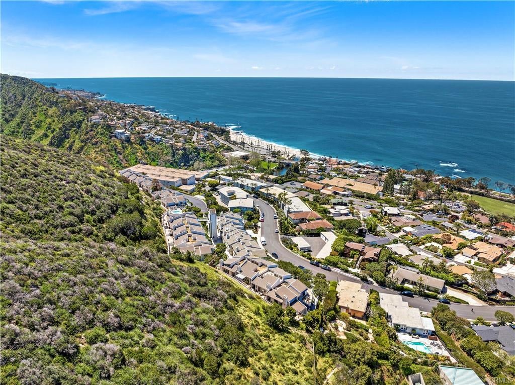 Aerial view of coastal homes, hillside, beach, and Pacific Ocean.