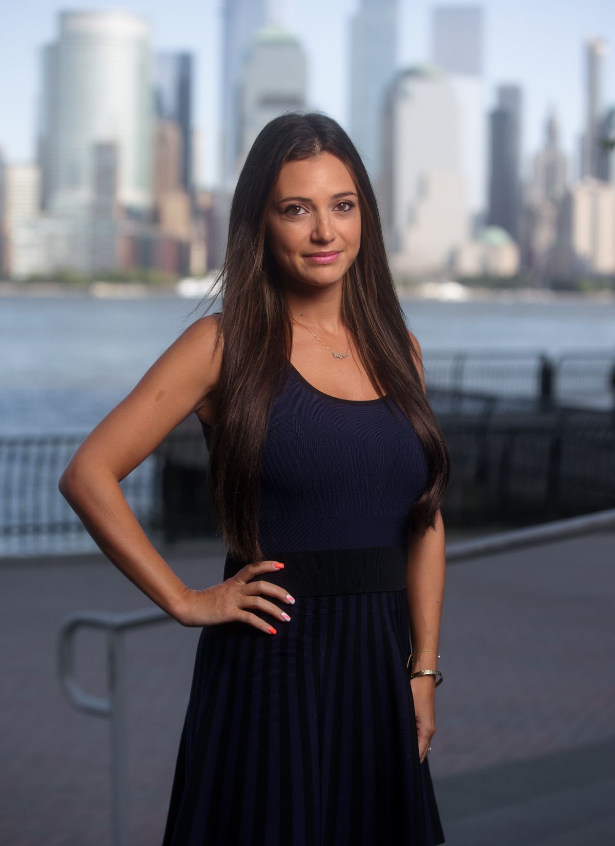 Rashella Zaslavsky, a real estate professional in a blue dress, standing in front of a captivating cityscape.