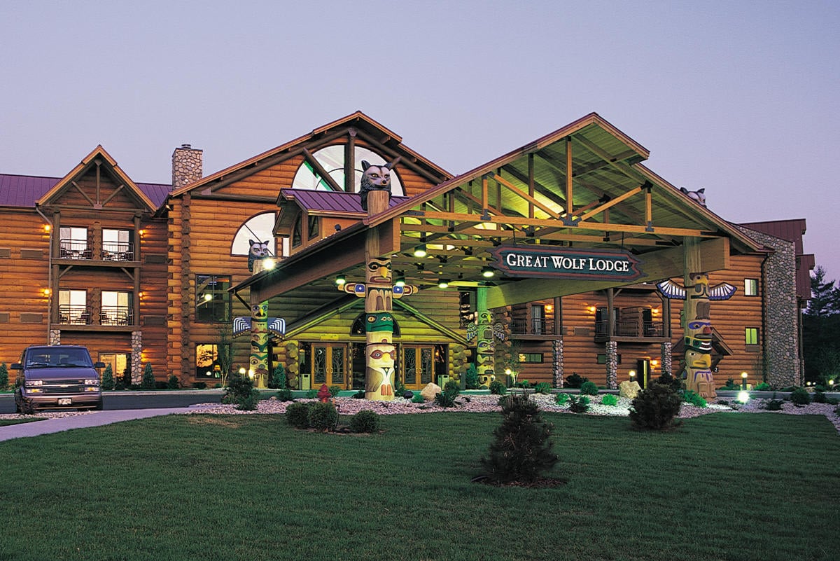 Great Wolf Lodge exterior with a covered entrance and carved totem poles at dusk.