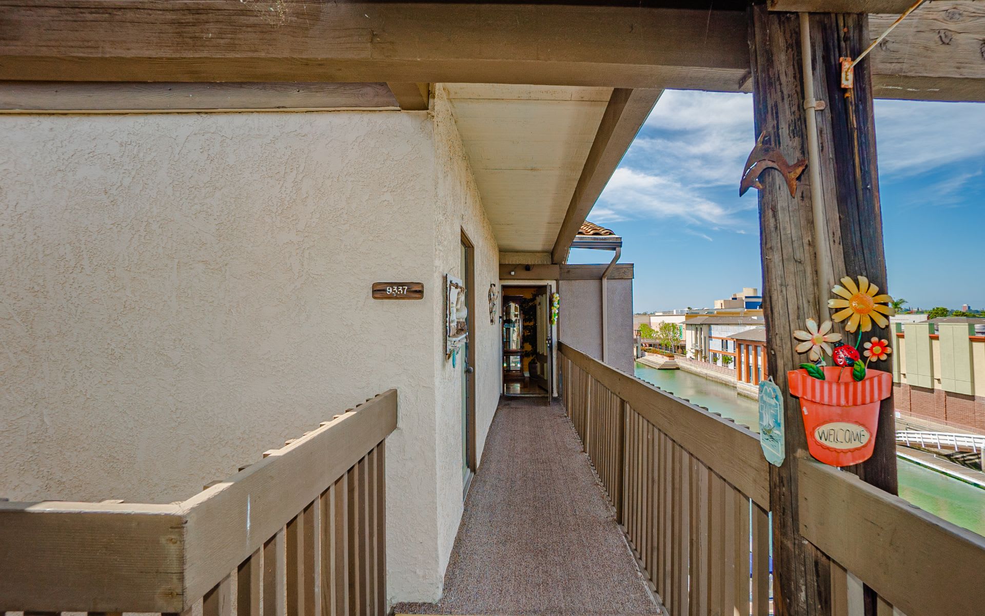 Covered walkway to the unit entrance, with wooden railings and a canal view.