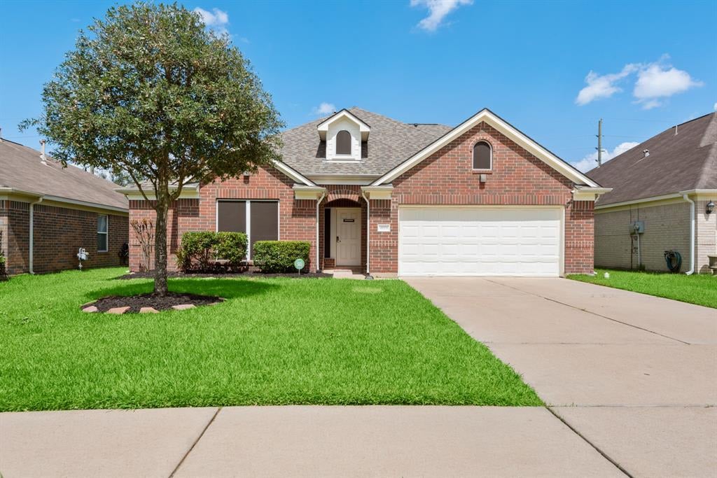 Red brick house with a white garage, broad lawn, and large front-yard tree.