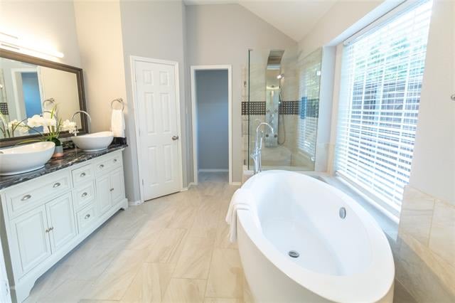 Bright bathroom with a freestanding soaking tub, double vanity, and glass-enclosed shower.