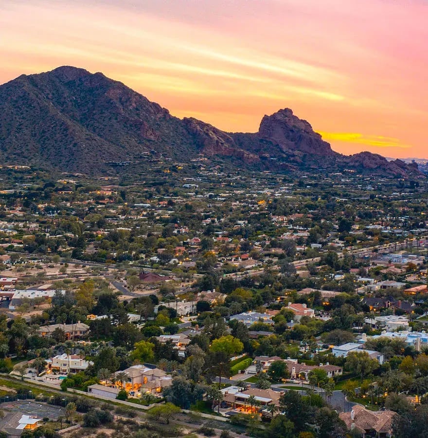 Panoramic Paradise Valley, bathed in sunset hues, sprawling luxury estates, and modern condos.