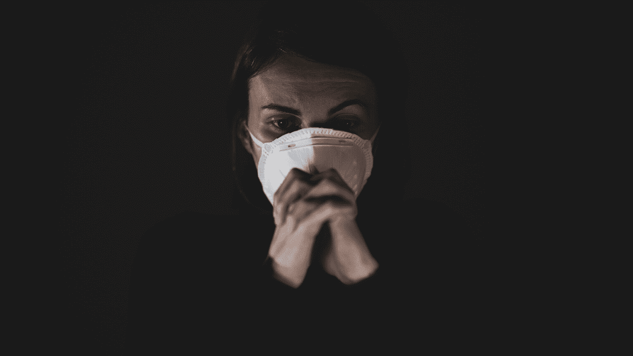 A person wearing a white protective face mask, often associated with preventing the spread of airborne illnesses or particulates. 