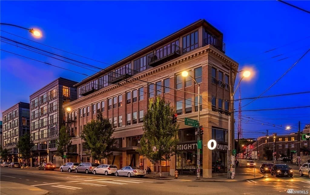 An impressive structure amidst a vibrant city scene, where cars line the street.