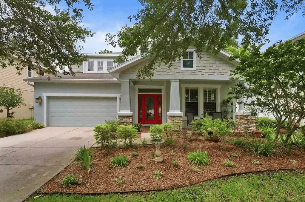 House with a bright red front door, double garage, and landscaped front garden.