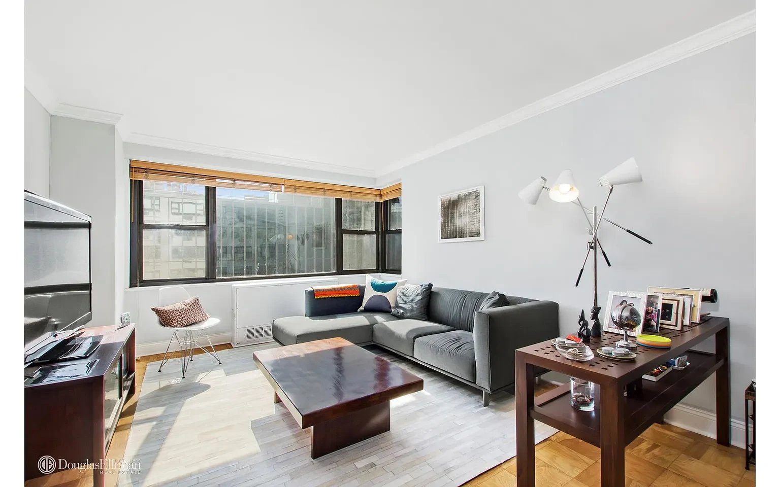 Living room with a gray sectional sofa, large corner windows, and contemporary furniture.