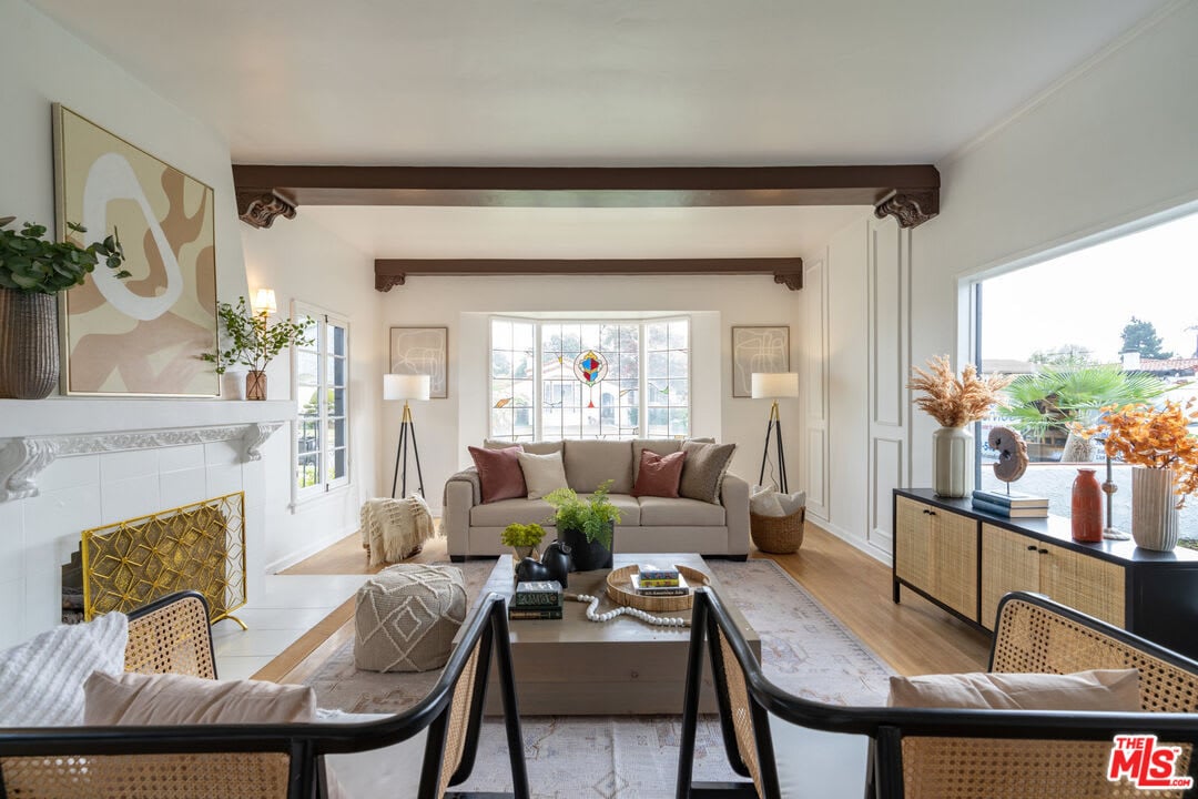 Bright living room with exposed beams, bay window, neutral sofa, modern decor, and large windows with natural light.