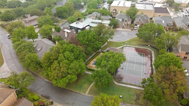 Aerial view of a tree-lined neighborhood with a fenced tennis court.