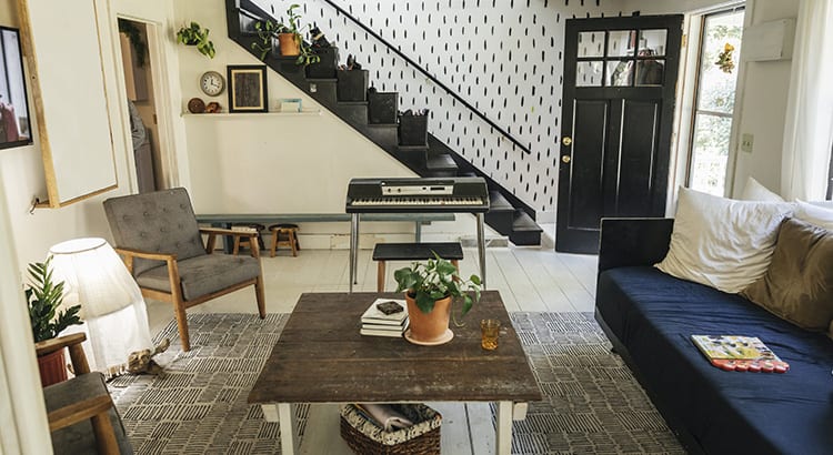An image of a cozy living room with a staircase in the background, featuring a coffee table, chairs, and a couch, suggesting themes related to home decor or interior design.
