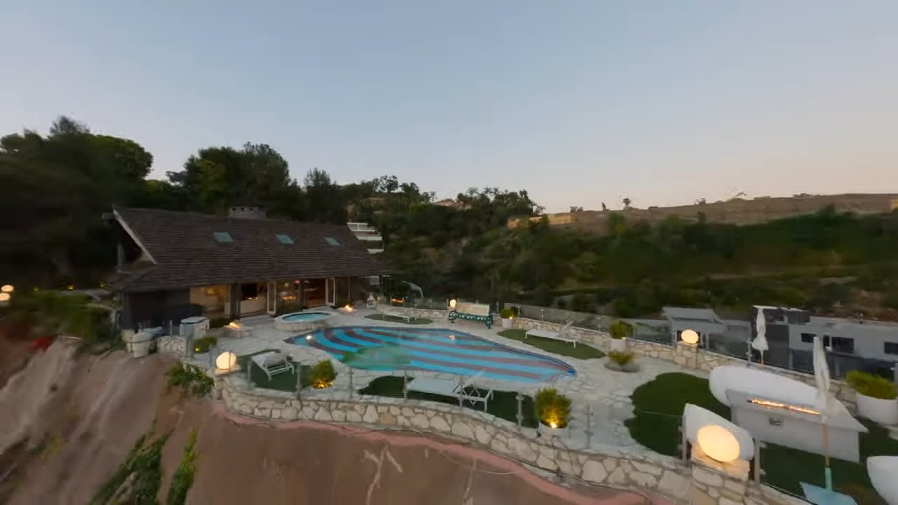 An aerial view of a modern house with a swimming pool and a patio.