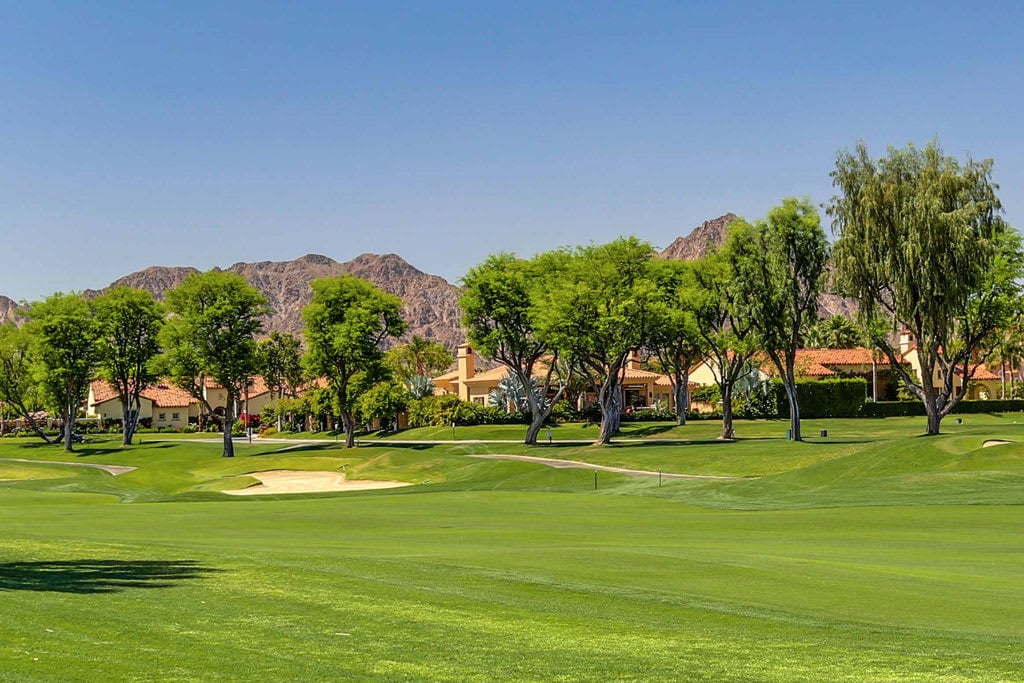 A lush green golf course with a sand trap in the foreground