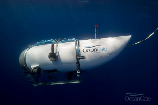 A small submarine floating on top of a body of water. The submarine is white and has a black dome on top. The water is blue and calm.