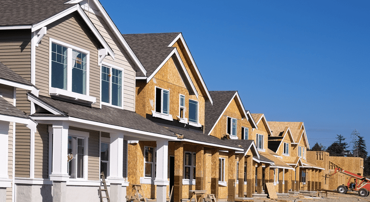 A row of houses in various stages of construction, showcasing scaffolding and building materials in a residential area