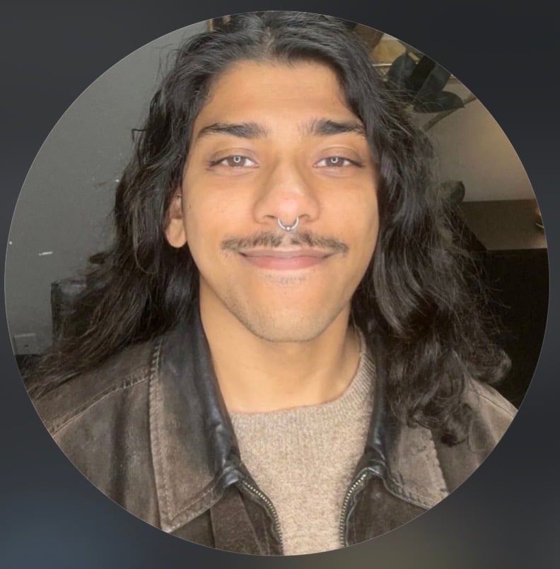 Sakib Mahbubullah with long dark hair and a septum ring, wearing a brown leather jacket.