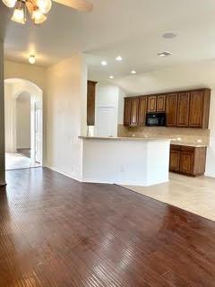 Open kitchen with a breakfast bar, dark wood cabinetry, and adjoining hardwood-floored living area.