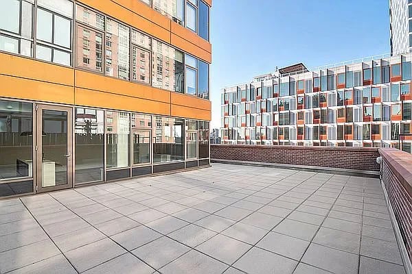 Tiled apartment terrace with an orange facade and views of neighboring modern buildings.