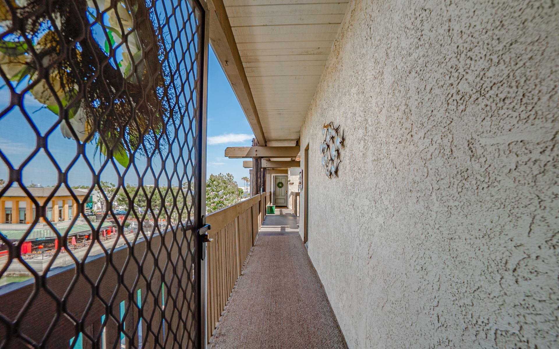Covered balcony walkway with a decorative security gate and wood railing.