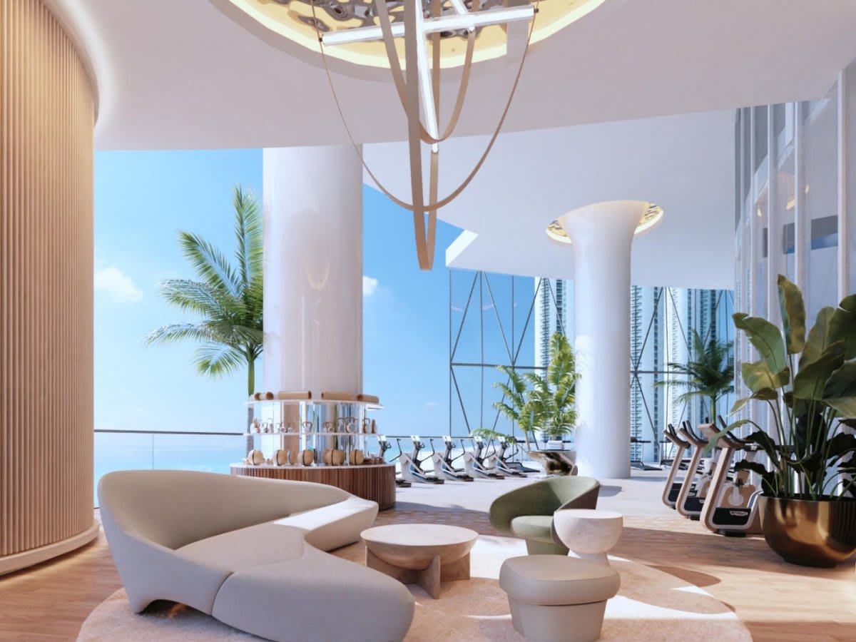 Fitness center with exercise machines, sculptural lounge seating, and water views through floor-to-ceiling windows.