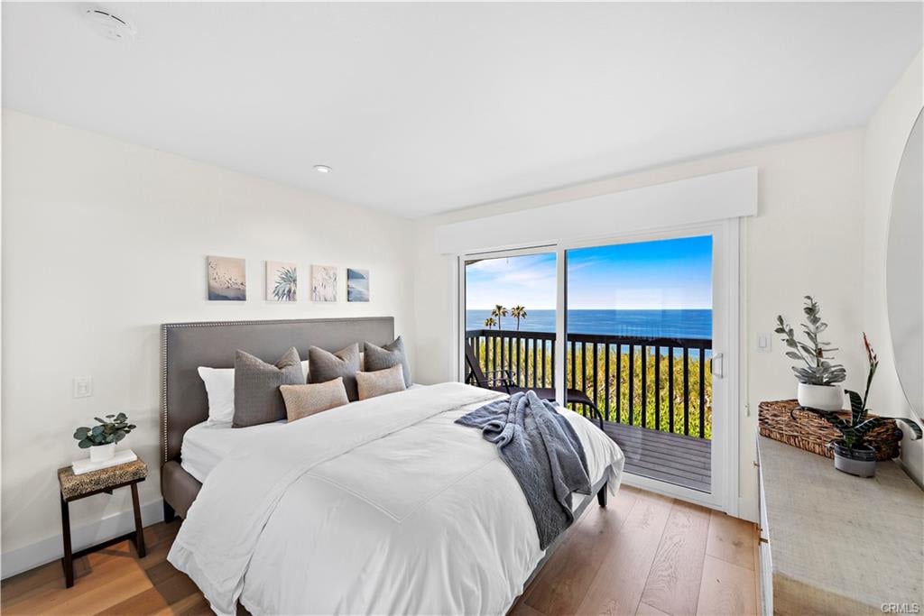 Staged bedroom with ocean views through sliding glass doors to a balcony.