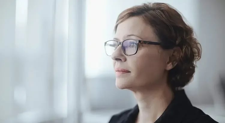 A profile of a woman wearing glasses, possibly a real estate agent or professional, in a thoughtful pose.