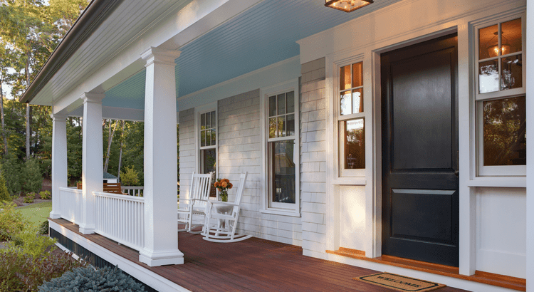 Front porch of a house featuring a wooden floor and white pillars supporting the roof. 