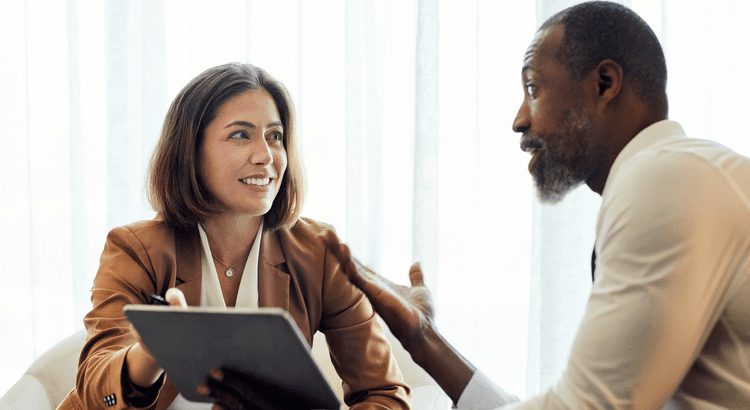 A man and woman engage in conversation while seated at a table, sharing ideas and enjoying each other's company.