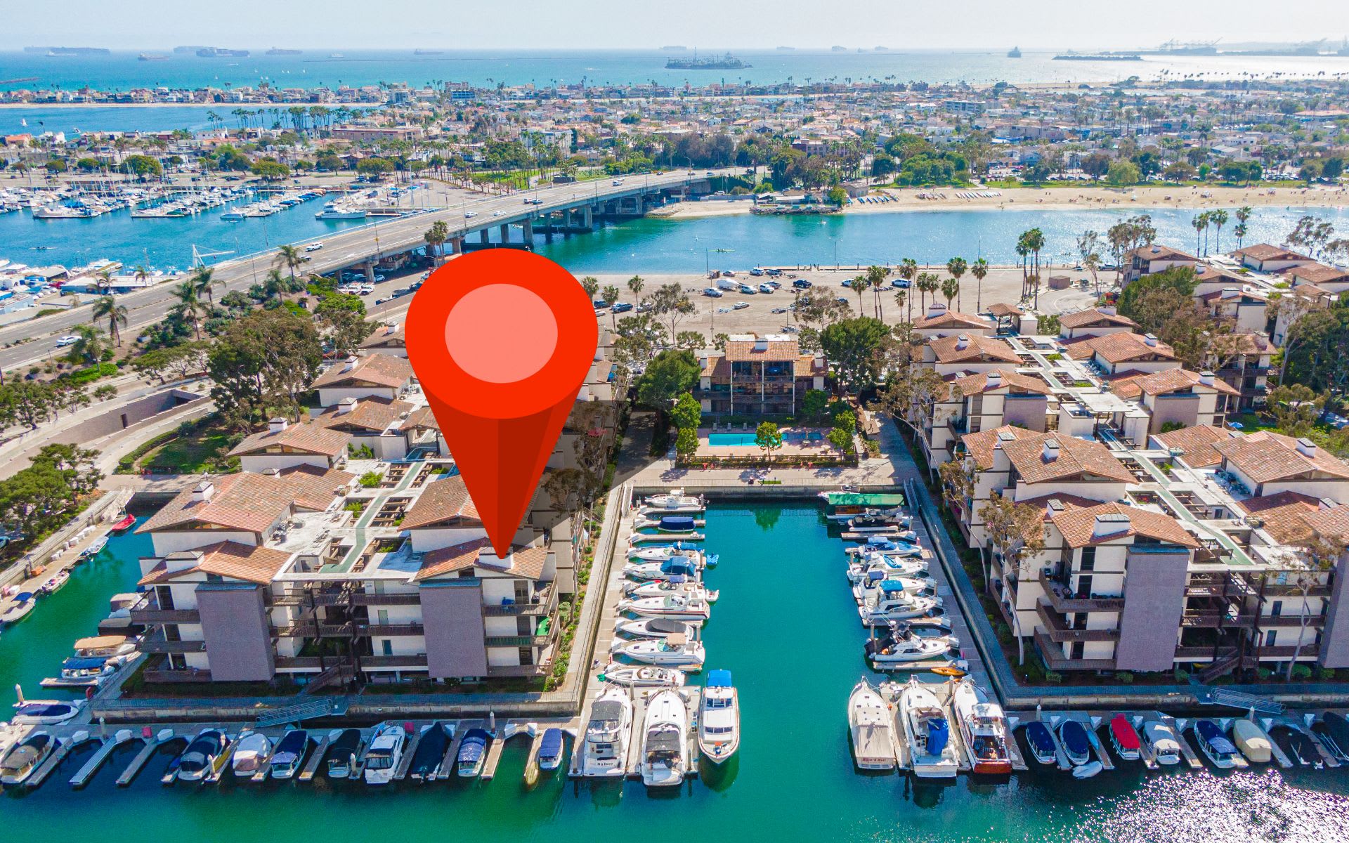 Waterfront condominium complex beside marina channels, with a red map pin marking a building.