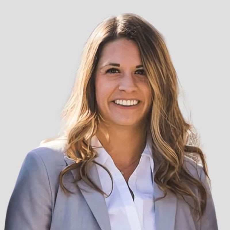 Ashley, smiling in a light gray blazer and white blouse.