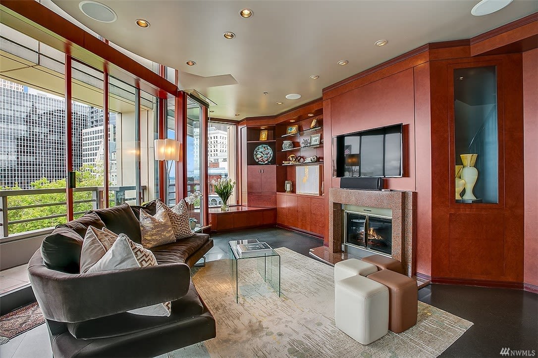 Luxury condo living room with rich wood tones, fireplace, and city views, offering sophisticated urban comfort.