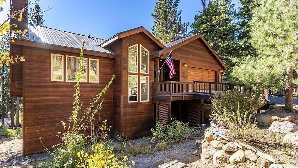 Cedar-sided mountain home with a metal roof, tall gable windows, a wraparound deck and boulder landscaping among pines and yellow fall aspens at 752 Geraldine Drive, Jennifer, Incline Village