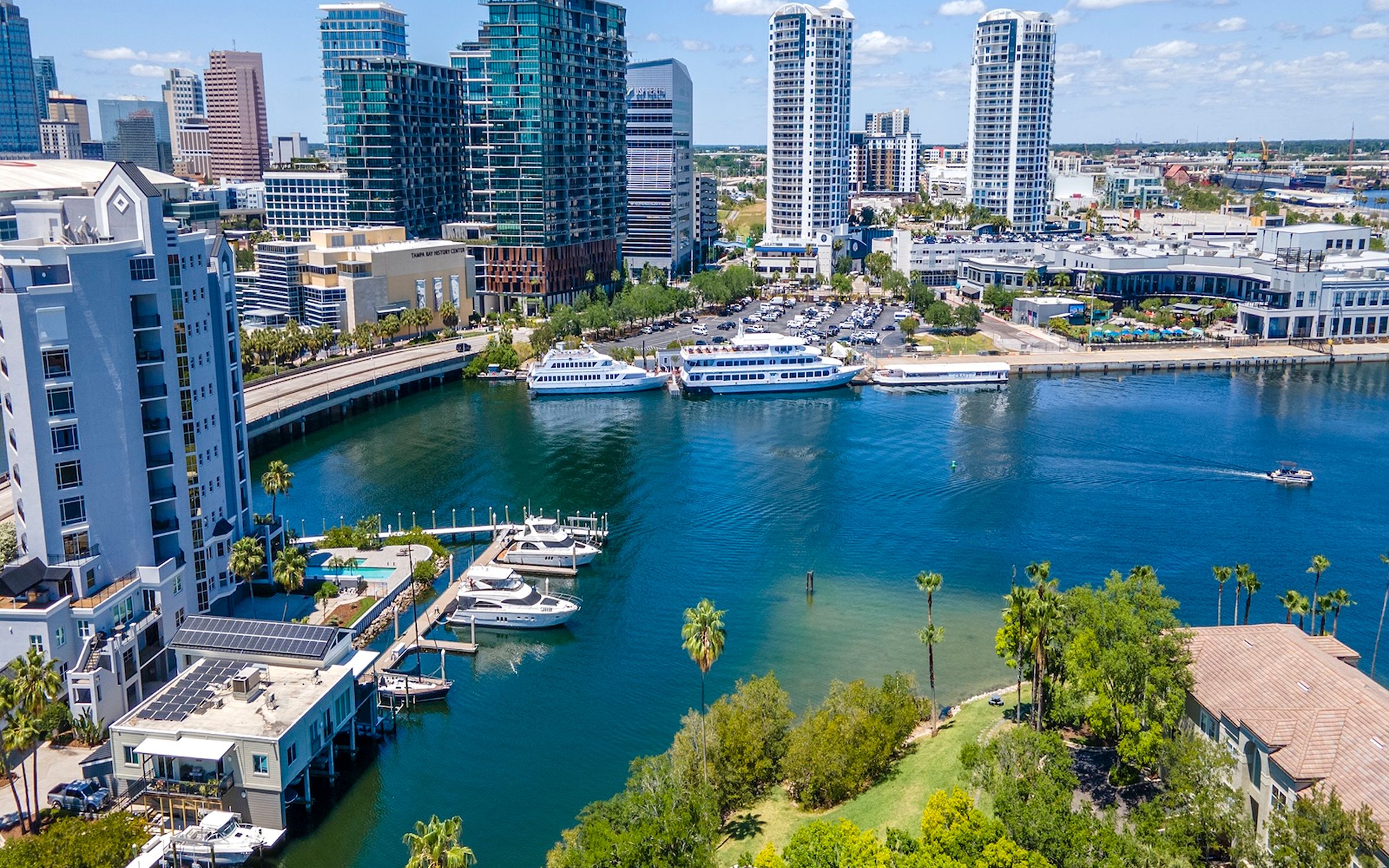 Aerial view of downtown Tampa's waterfront with high-rise condos, a marina, and boats along the channel.