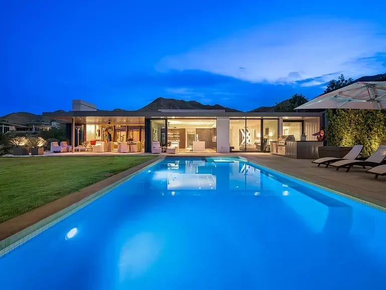 A modern luxury house with a sparkling swimming pool in the foreground