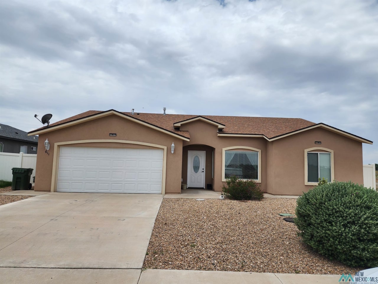 A brown house with a white garage door and a driveway.