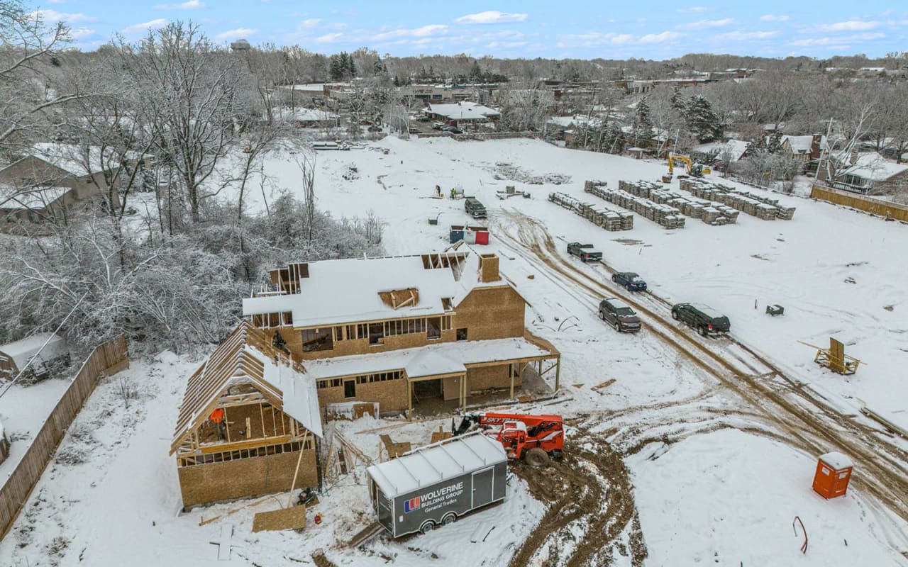 A house under construction in a snow-covered trees and a mountain range in the background