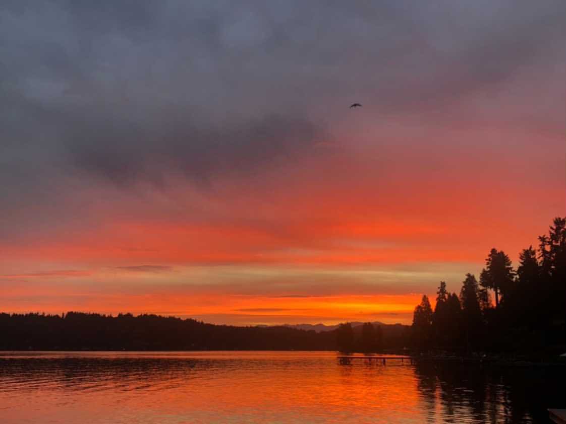 A sunset over a lake with a dock and boats in the water