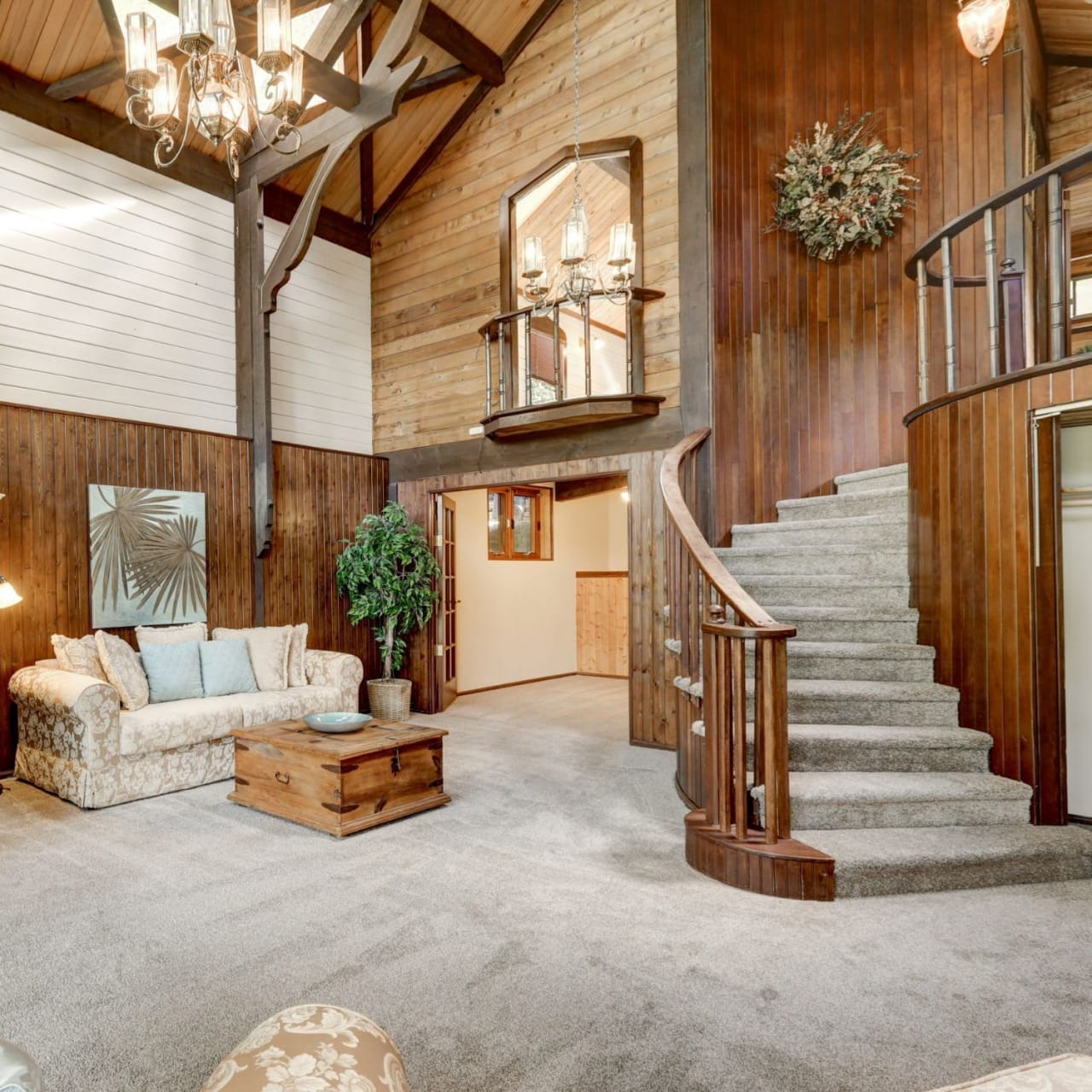 A modern living room with a light-colored couch, coffee table, and a spiral staircase made of wood.