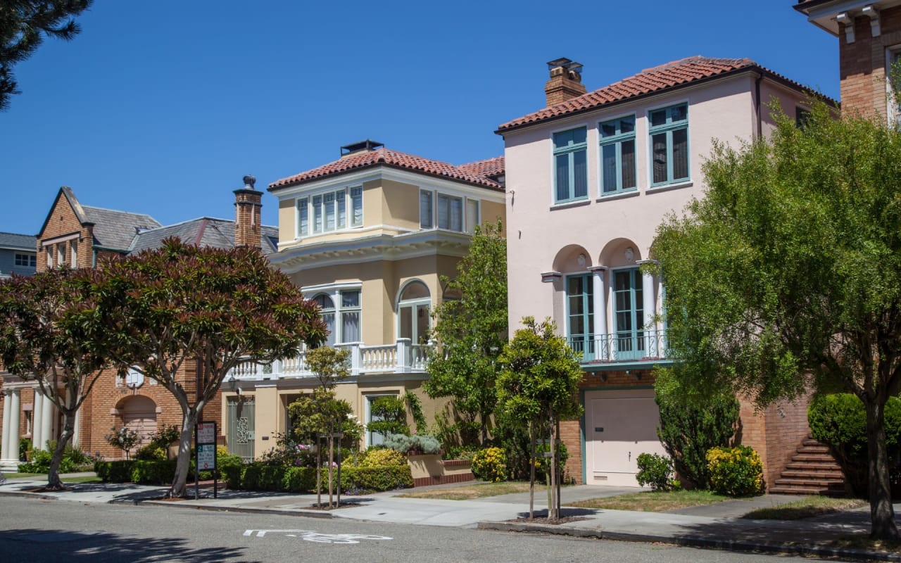 A row of colorful houses with neatly trimmed lawns on a quiet suburban street