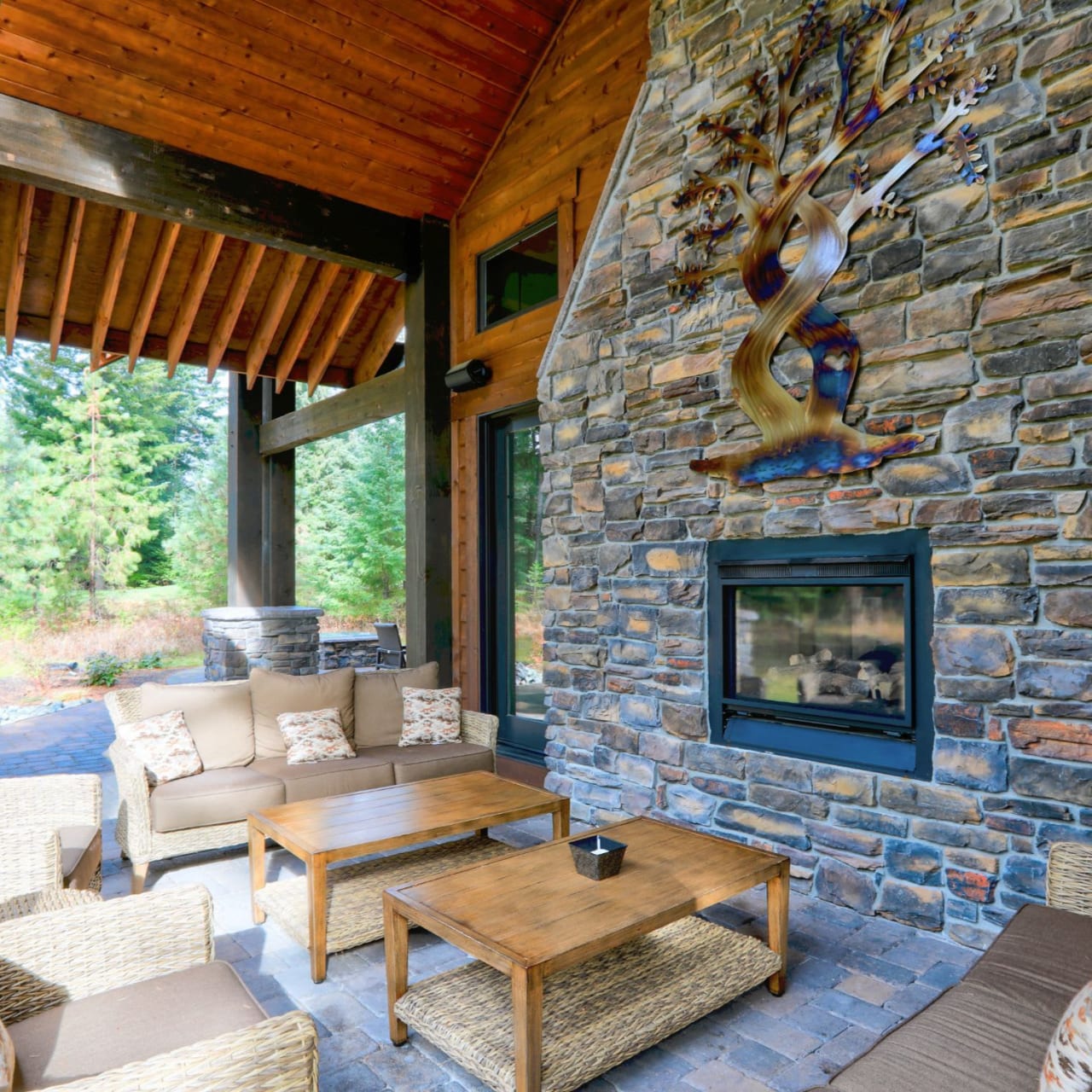 An outdoor living space with a fireplace made of light-colored stone.