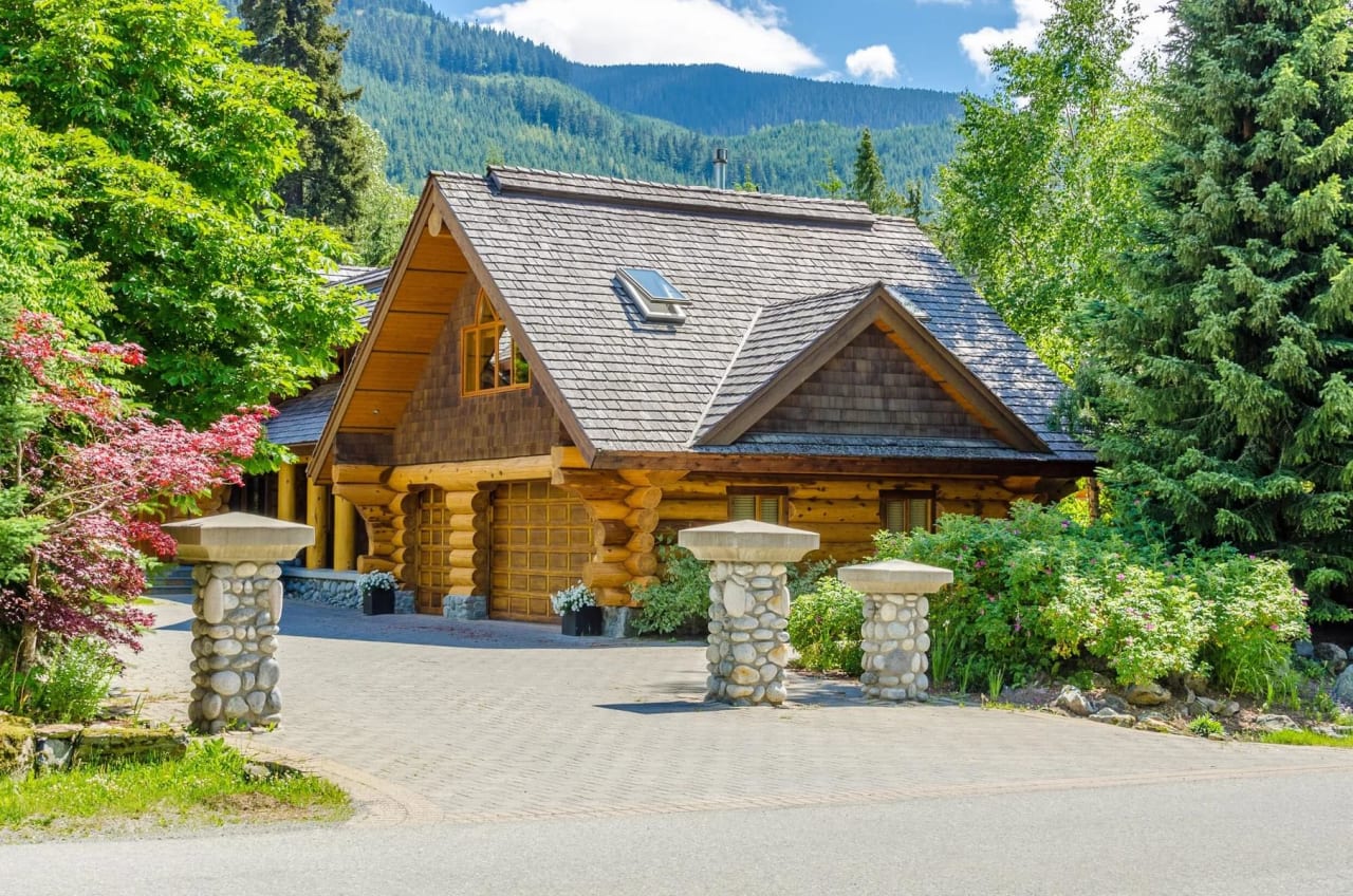 A rustic wooden house with a stone foundation and a sloped roof