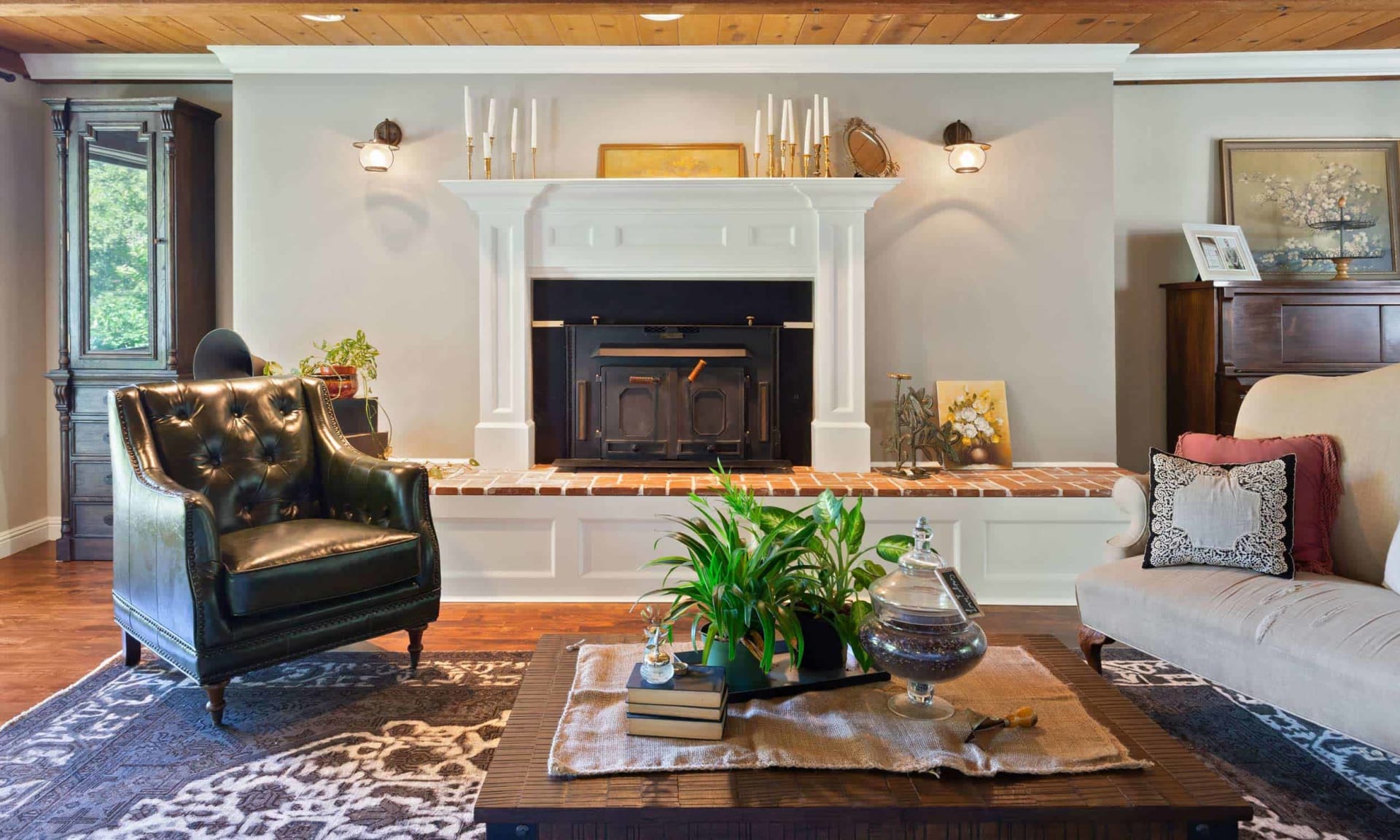 Living room with a white fireplace, black wood stove, and exposed wood-plank ceiling.