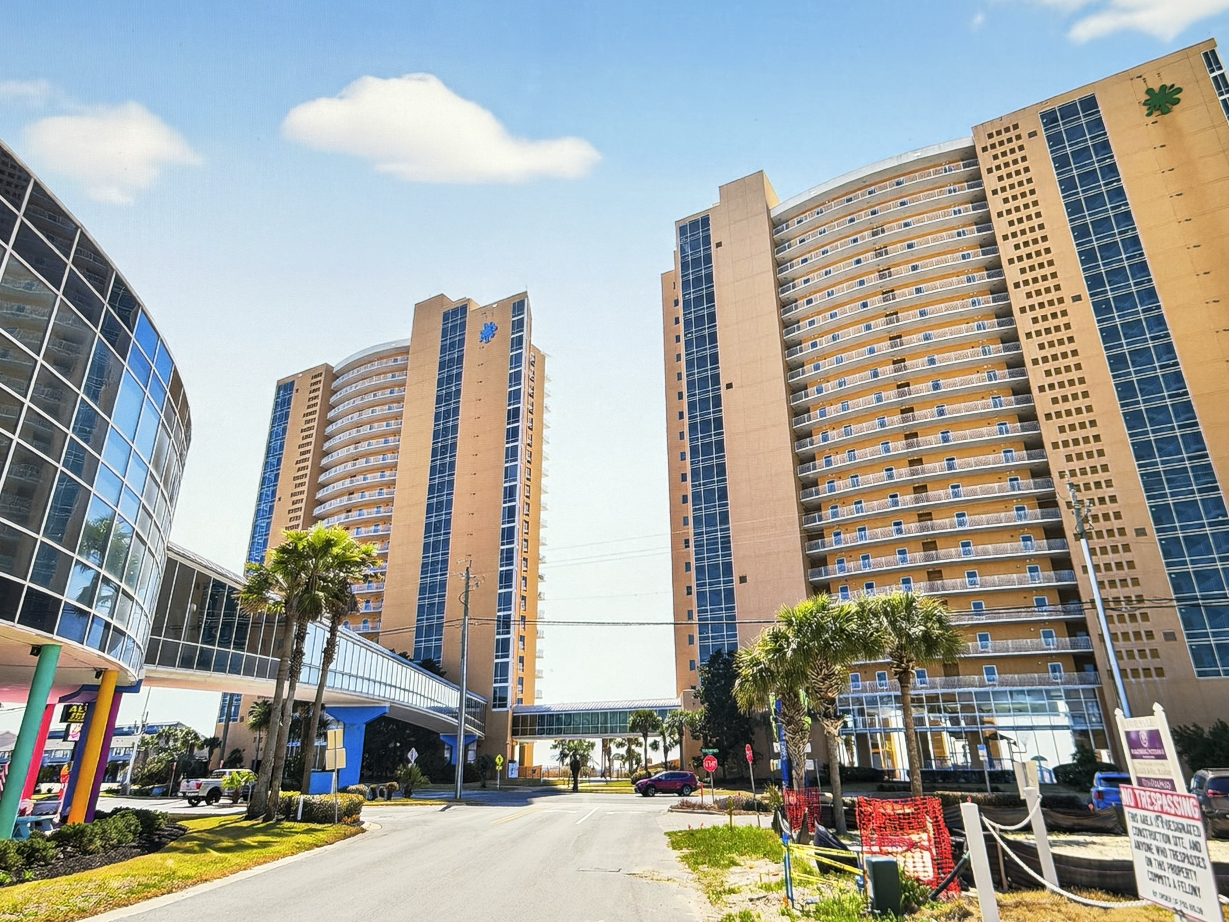 Street-level view of Splash Beach Resort condo towers and pedestrian skybridge in Panama City Beach Florida