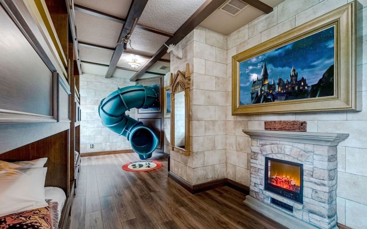 A bedroom with a brightly colored plastic slide that winds through the room.