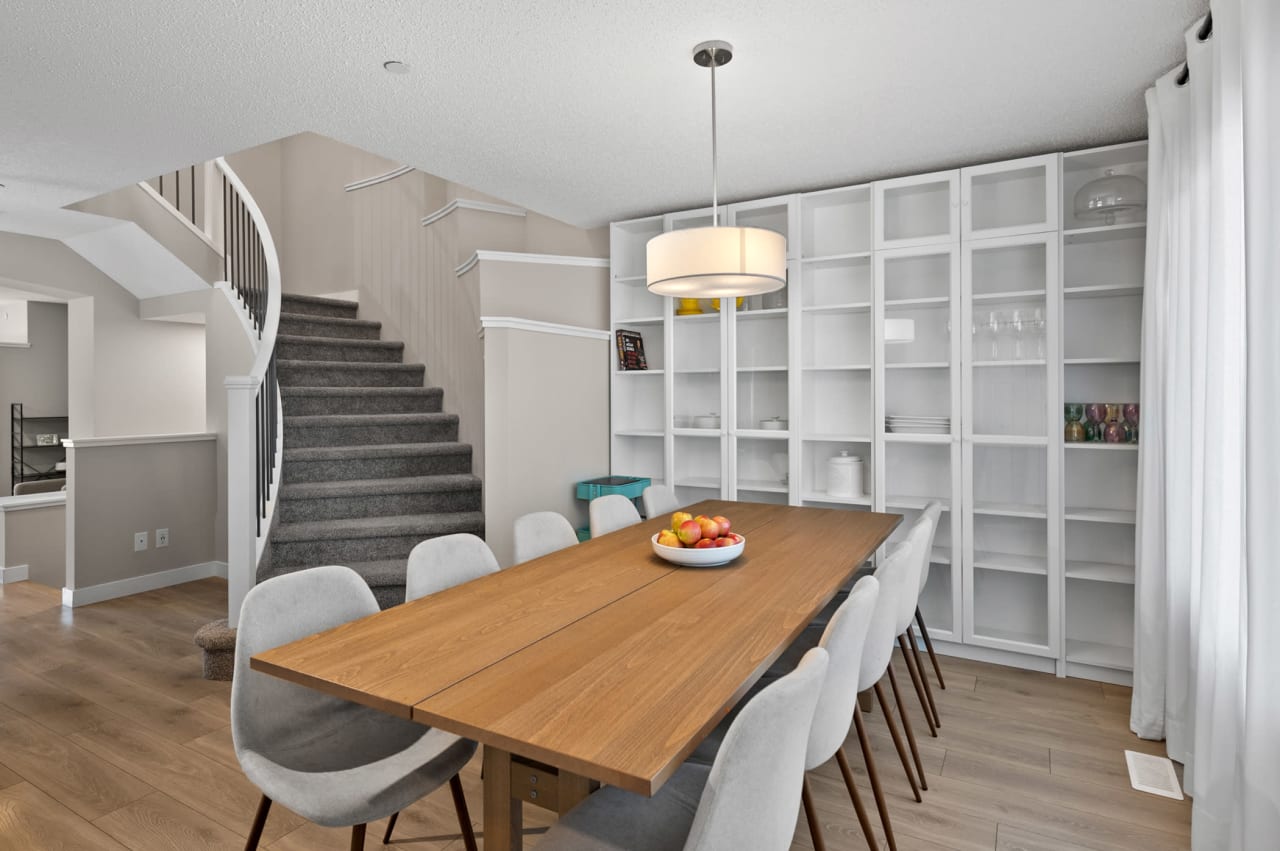 A wooden dining table with six white chairs in a modern dining room