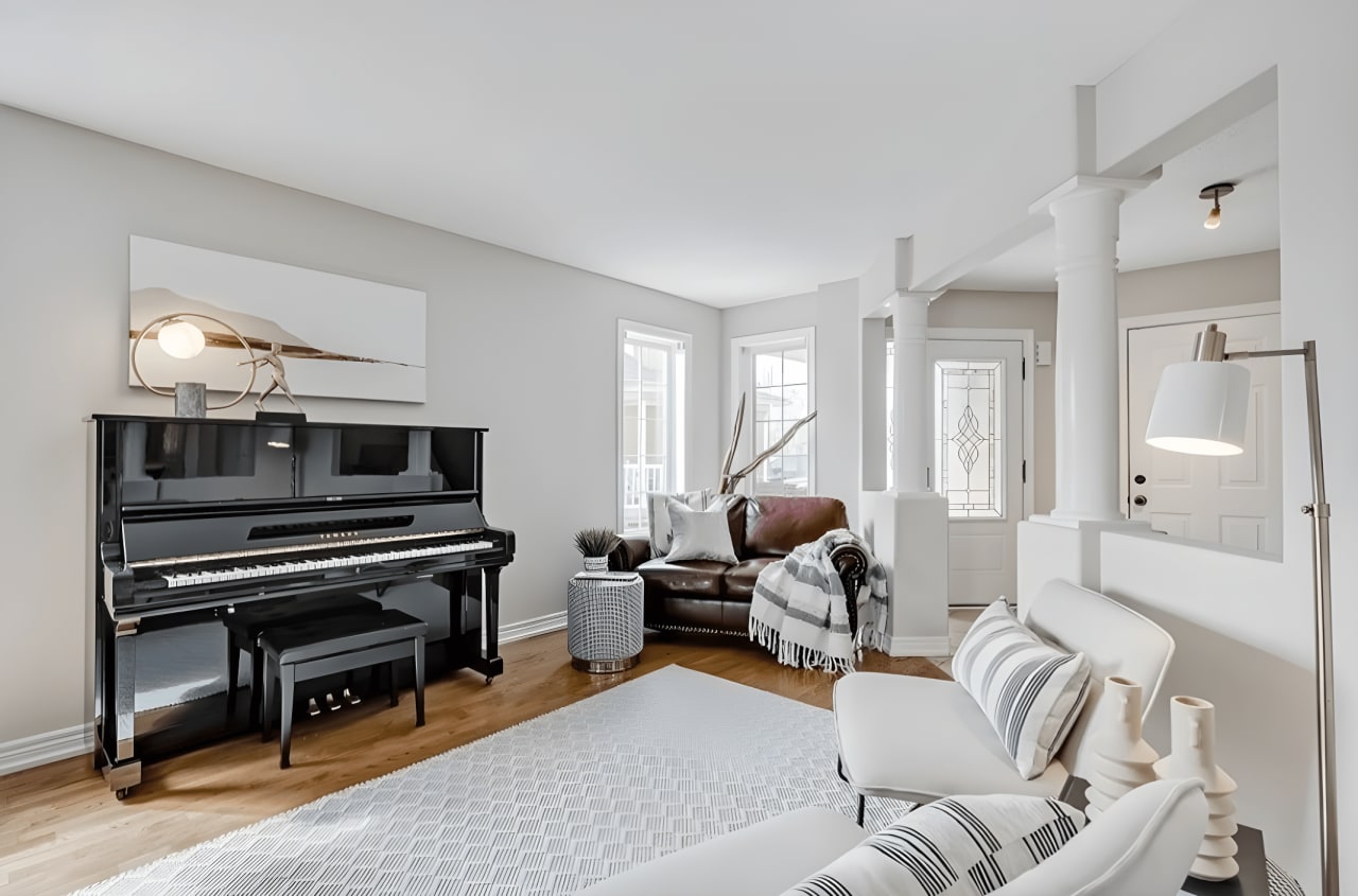 A living room with a black piano, a brown couch, and two white chairs.