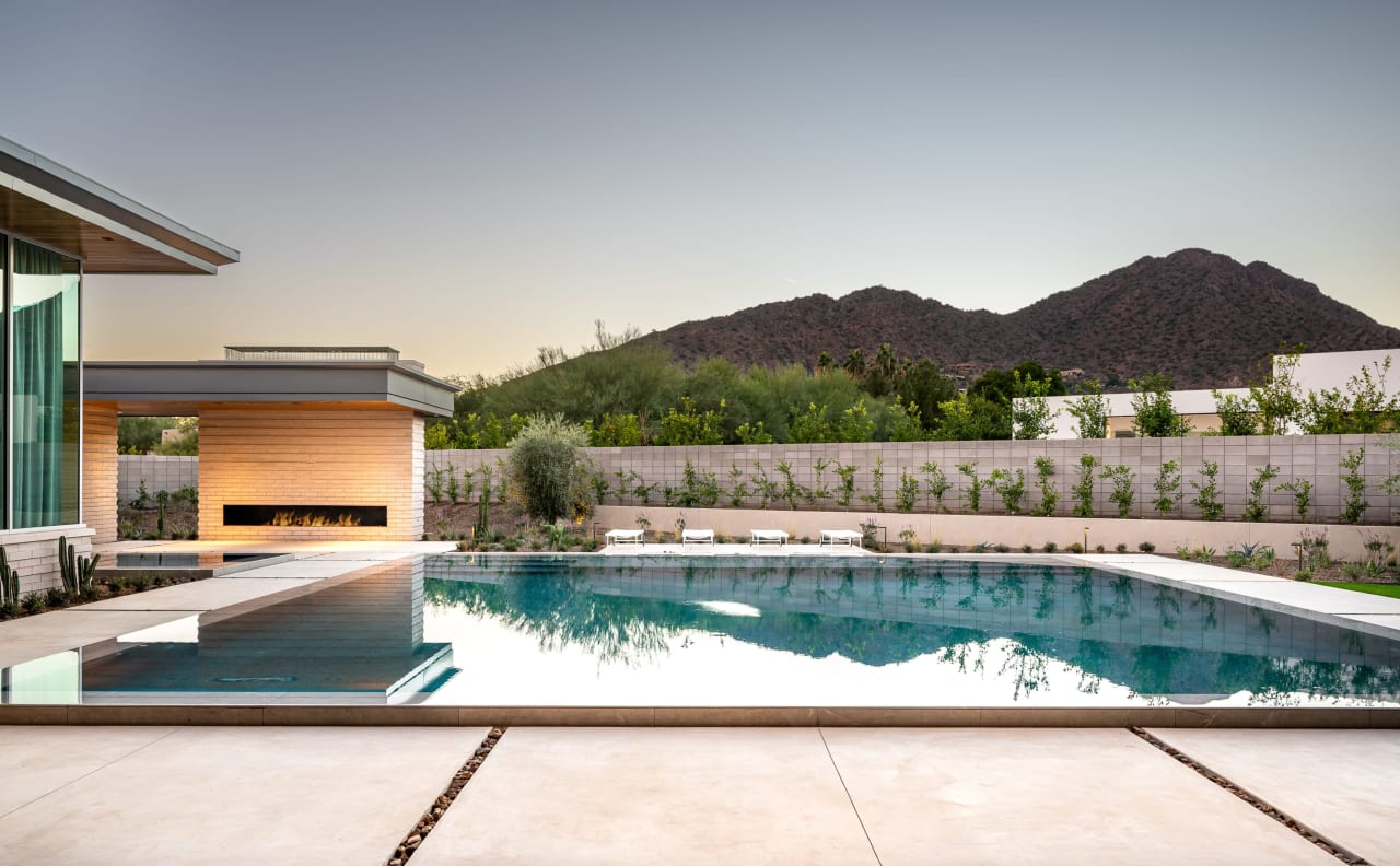 Floating pool and stone fireplace in backyard with mountain views