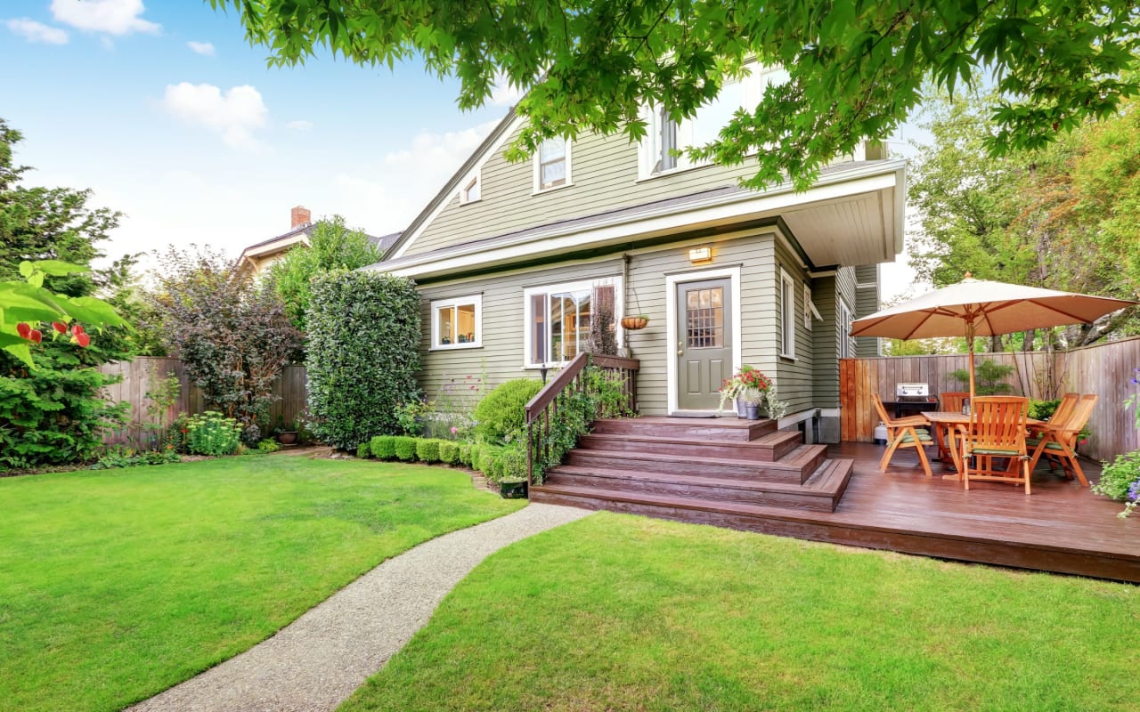 A two-story house with a green exterior and a wooden deck